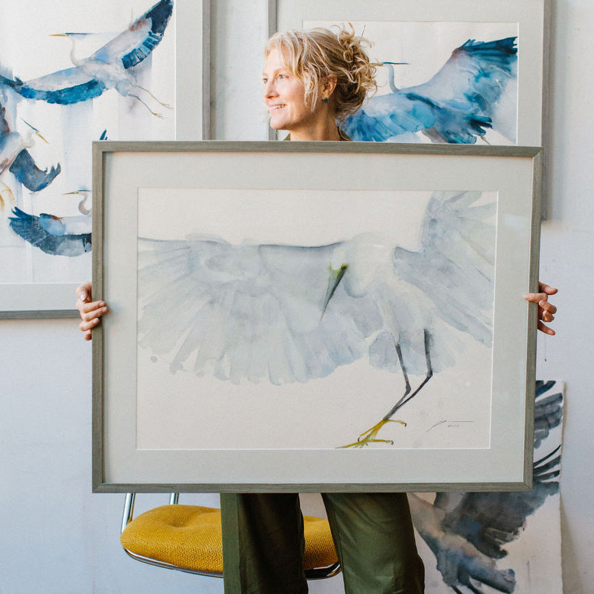 Holly Wach holding large framed original bird watercolor artwork