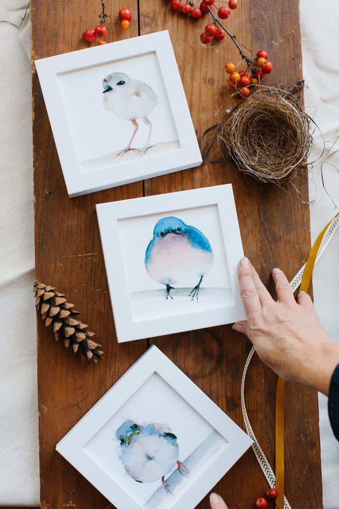 a watercolor artist holding a framed picture of a bird