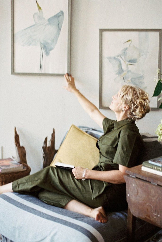 Holly Wach (artist) sitting in a chair showing her original bird watercolor art