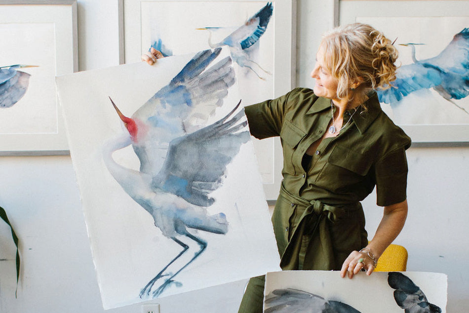 Holly Wach holding prints of her watercolor bird artwork