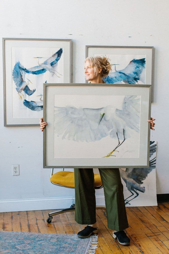 Holly Wach (artist) standing in front of a wall showing her original bird art watercolor